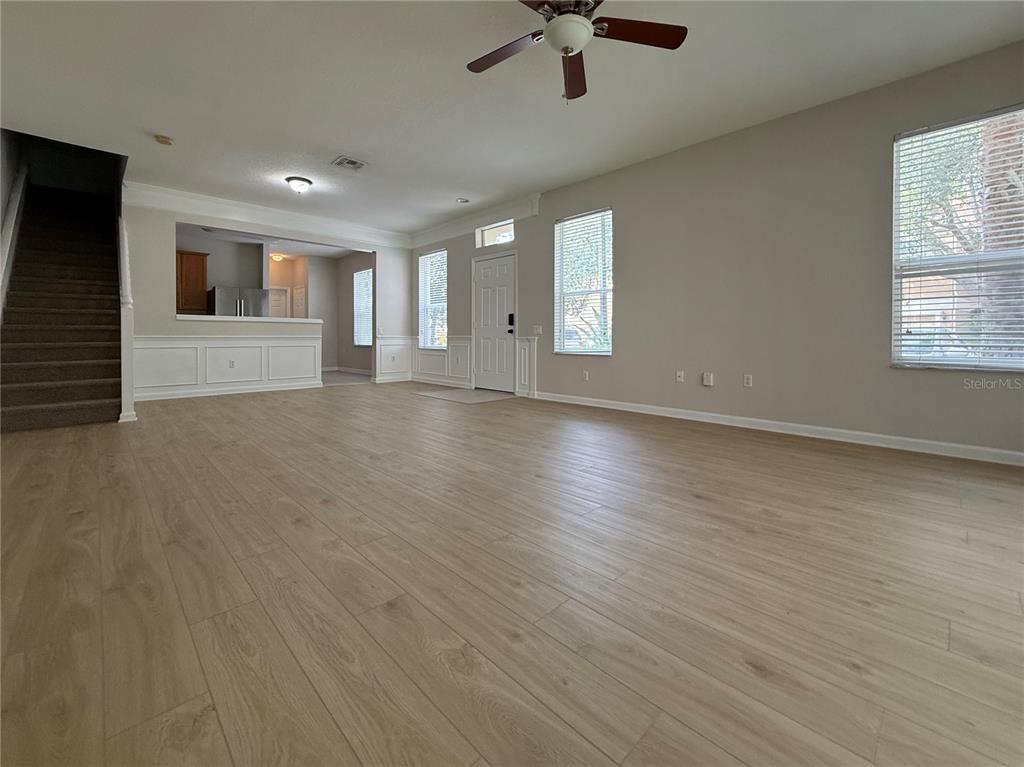 An open-concept living area features wood-look flooring, a staircase, and a view into the kitchen — 6485 RANELAGH DRIVE UNIT 101, ORLANDO, FL