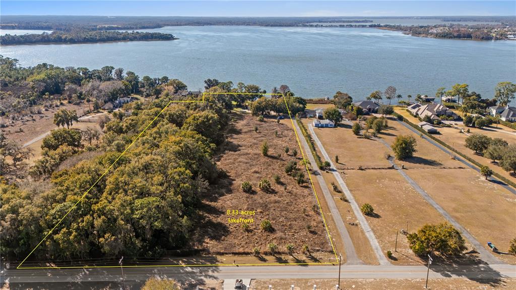 An aerial view shows a large, rectangular vacant lot with trees and lakefront access — 6136 DORA DRIVE, MOUNT DORA, FL