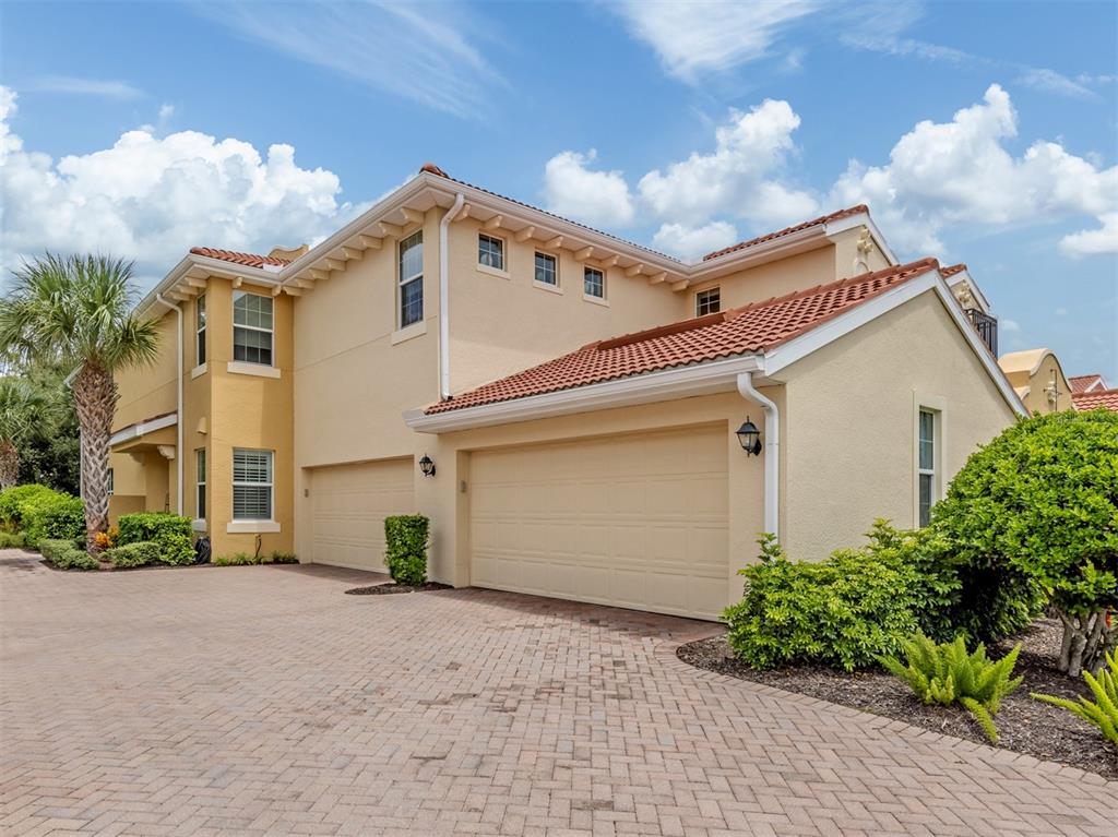 A two-story house with a tan stucco exterior, tile roof, and a paved driveway — 170 BELLA VISTA TERRACE UNIT 20C, NORTH VENICE, FL