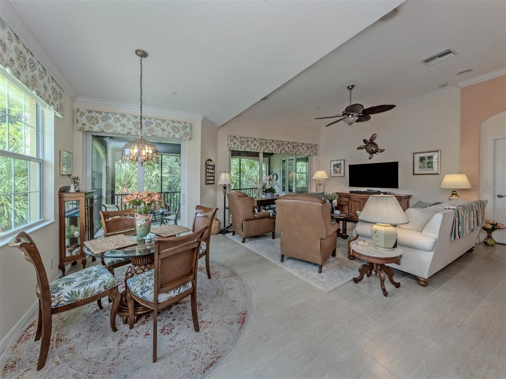 An open-concept living and dining area features tile floors, a glass-top table, and sliding glass doors — 170 BELLA VISTA TERRACE UNIT 20C, NORTH VENICE, FL