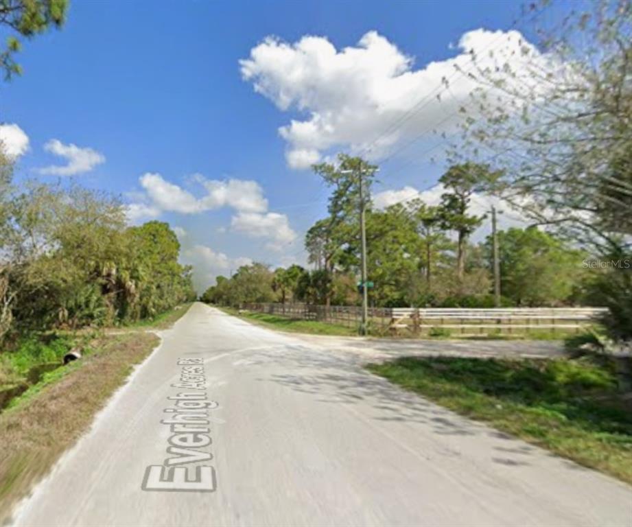 A dirt road leads toward a white fence and trees under a blue sky — 13649 & 13601 MURCOTT AVENUE, CLEWISTON, FL