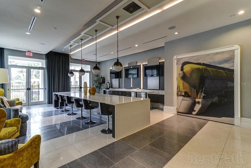 A modern lounge area features a long kitchen island, bar seating, and a large train mural — 1688 CELEBRATION BOULEVARD UNIT The Audrey, CELEBRATION, FL