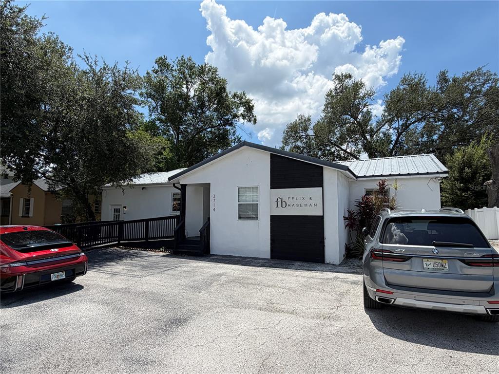 A white single-story building with a black accent wall and two parked cars in front — 3714 W HORATIO STREET, TAMPA, FL