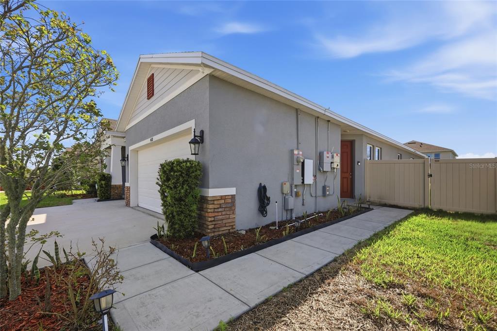 A side view of a gray house with a garage, a walkway, and a fence — 468 HALTER DRIVE, APOPKA, FL