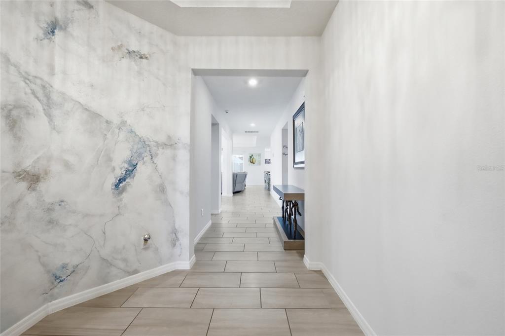 A hallway features light tile flooring, a marble-patterned accent wall, and a console table — 468 HALTER DRIVE, APOPKA, FL