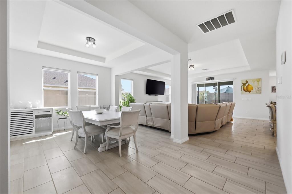 An open-concept dining area and living room with light tile flooring and white walls — 468 HALTER DRIVE, APOPKA, FL