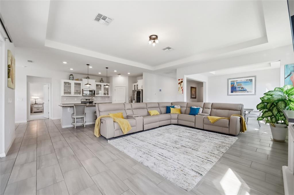 A spacious open-concept living room features a large sectional sofa, tile flooring, and kitchen area — 468 HALTER DRIVE, APOPKA, FL
