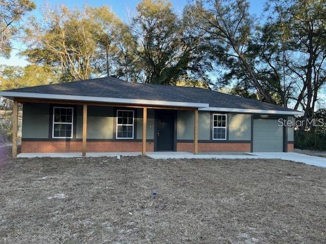 A single-story house with a covered porch, brick base, and attached garage — 3779 SE 140TH LANE, SUMMERFIELD, FL