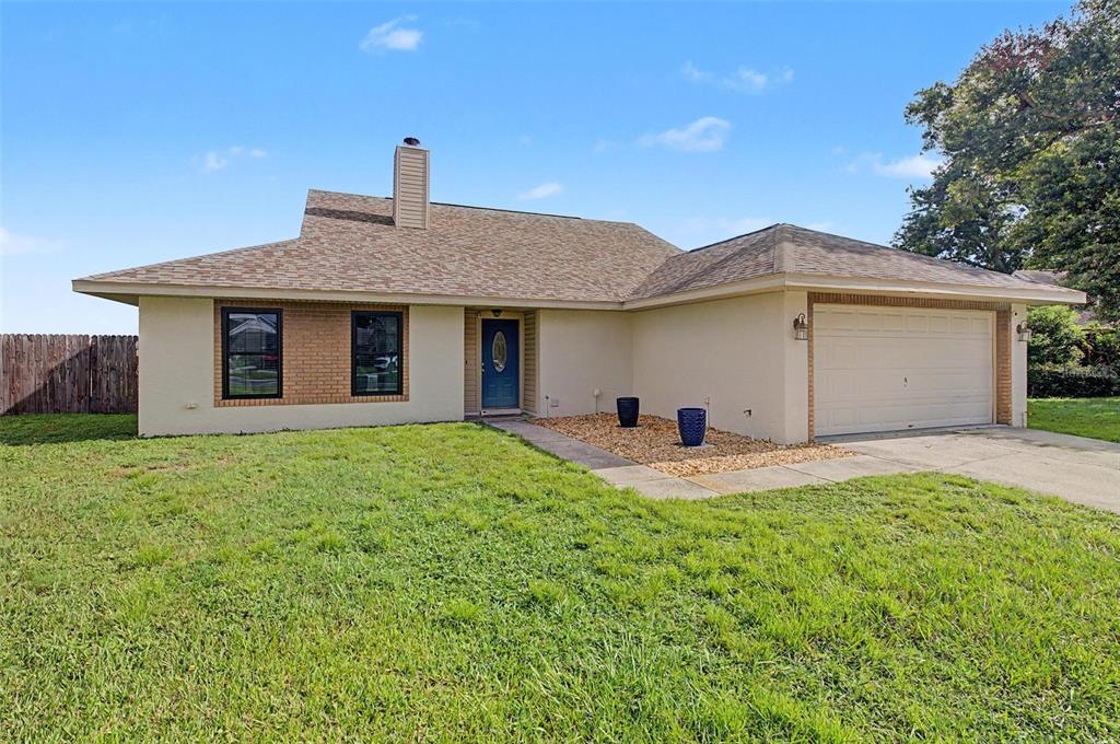 A single-story house with a tan stucco exterior, brick accents, and an attached two-car garage — 1917 REDBRIDGE DRIVE, BRANDON, FL