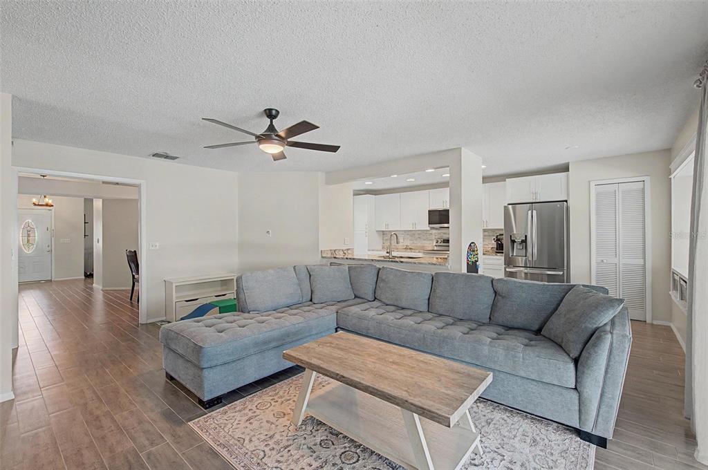 A living room with a gray sectional sofa, wood coffee table, and an open kitchen — 1917 REDBRIDGE DRIVE, BRANDON, FL