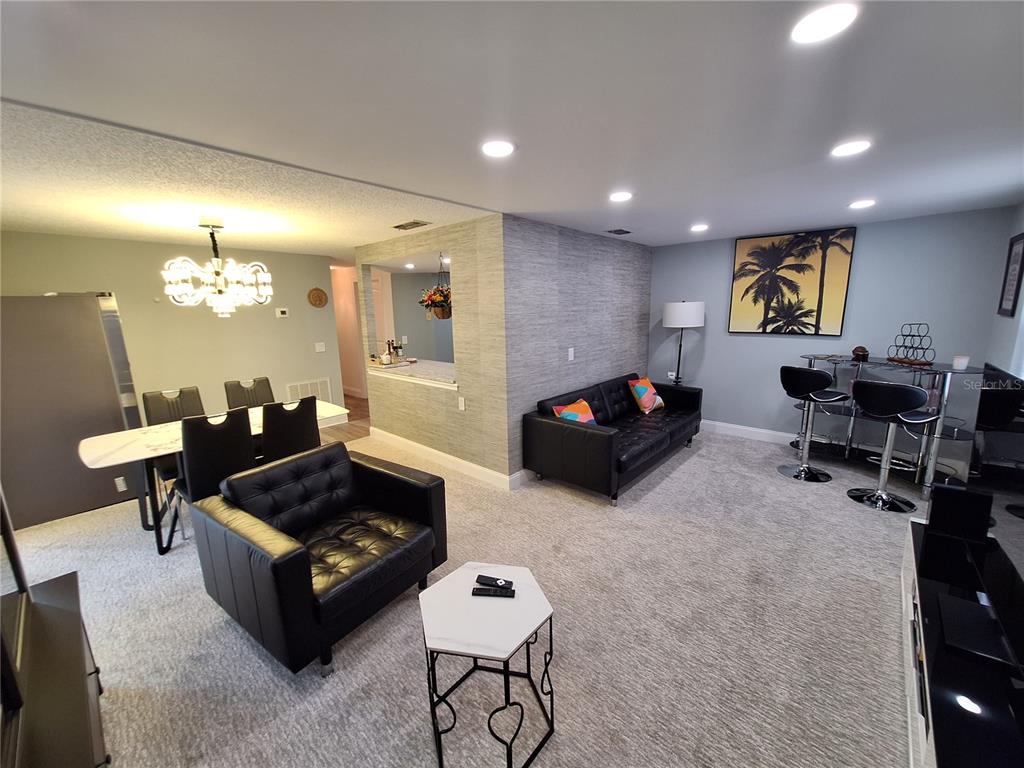 A living room and dining area feature black leather furniture, gray carpeting, and recessed lighting — 4022 BEAVER LANE UNIT 1000G, PORT CHARLOTTE, FL