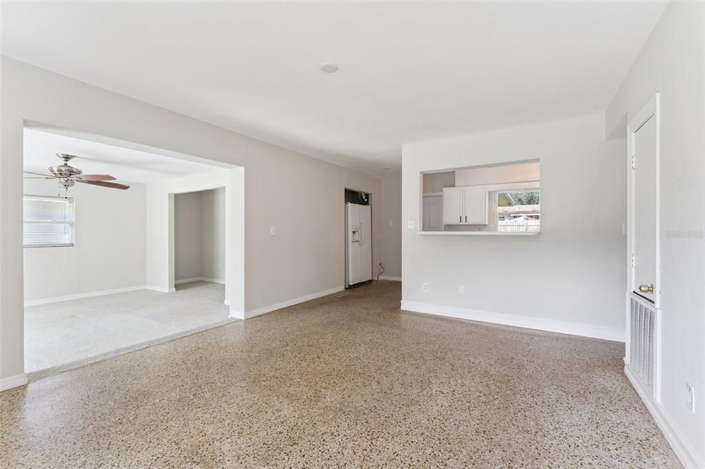 A living area with terrazzo flooring features a pass-through window to the kitchen — 108 ALEXANDRIA AVENUE, MINNEOLA, FL