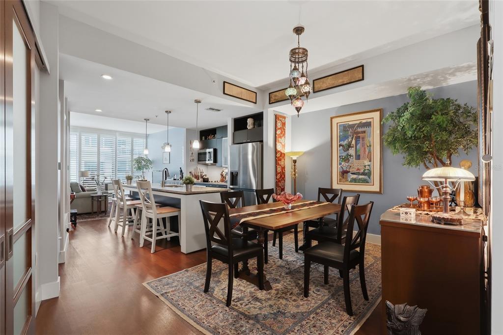 An open-concept dining area and kitchen with hardwood floors, a wooden table, and pendant lighting — 111 N 12TH STREET UNIT 1521, TAMPA, FL