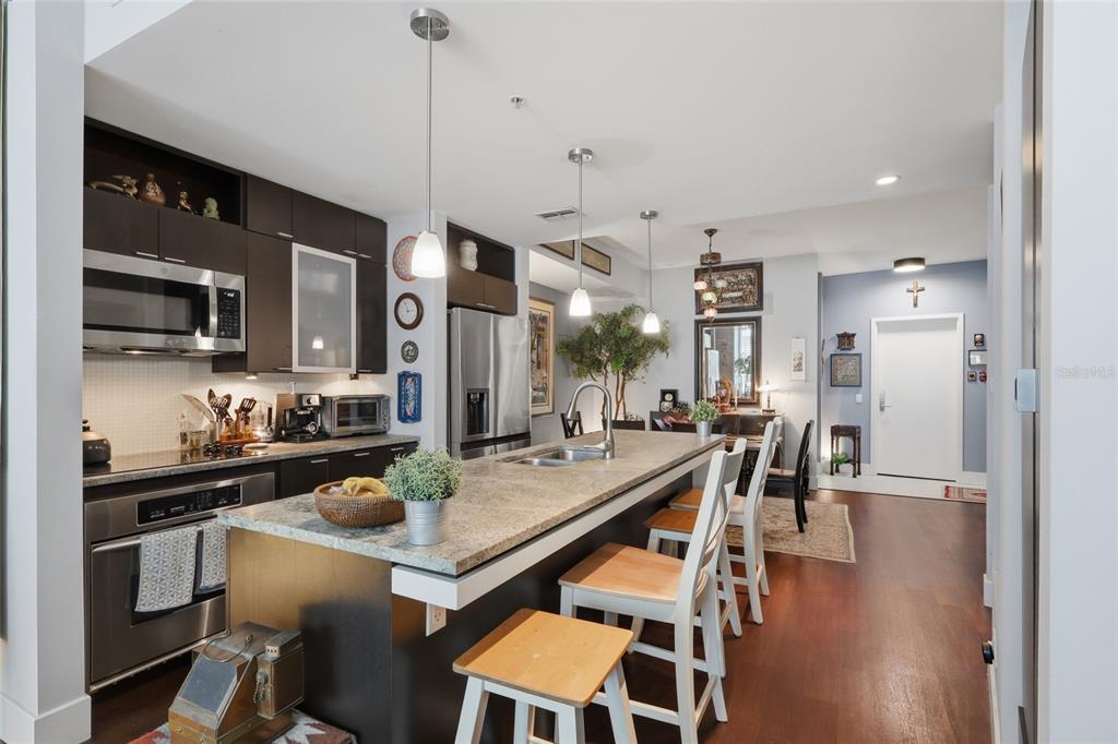 A kitchen with dark cabinets, granite countertops, a large island, and bar stools — 111 N 12TH STREET UNIT 1521, TAMPA, FL