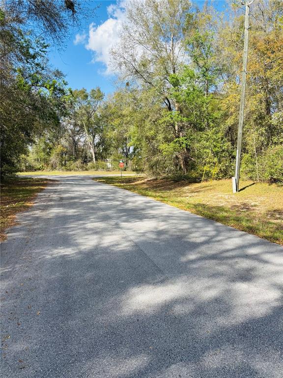 A paved road leads toward a stop sign surrounded by trees and a utility pole — 0 SW 19TH AVE ROAD UNIT 3, OCALA, FL
