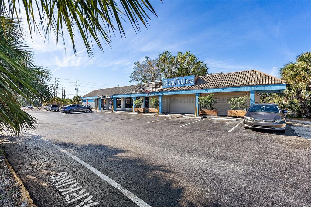 A single-story commercial building with a parking lot and palm trees in the foreground — 7612 BLIND PASS ROAD, ST PETE BEACH, FL
