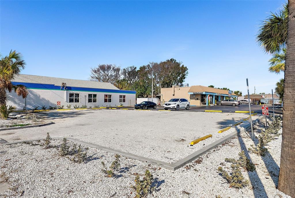 A gravel parking lot sits in front of a commercial building and a restaurant — 7612 BLIND PASS ROAD, ST PETE BEACH, FL