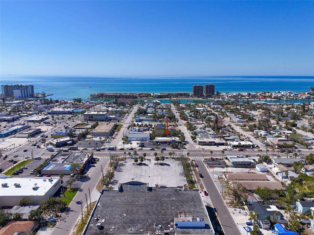 An aerial view shows a commercial building with a red arrow pointing to its roof — 7612 BLIND PASS ROAD, ST PETE BEACH, FL