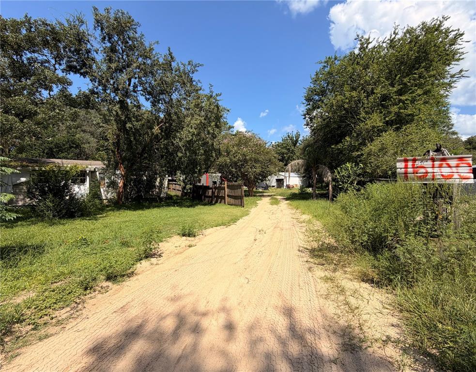 A dirt driveway leads toward a house and a detached garage on a wooded lot — 16100 SE 253RD COURT, UMATILLA, FL