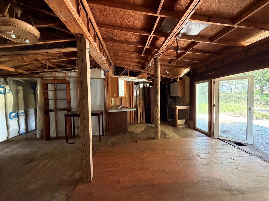 An unfinished room features exposed wooden ceiling beams, plywood flooring, and glass sliding doors — 16100 SE 253RD COURT, UMATILLA, FL