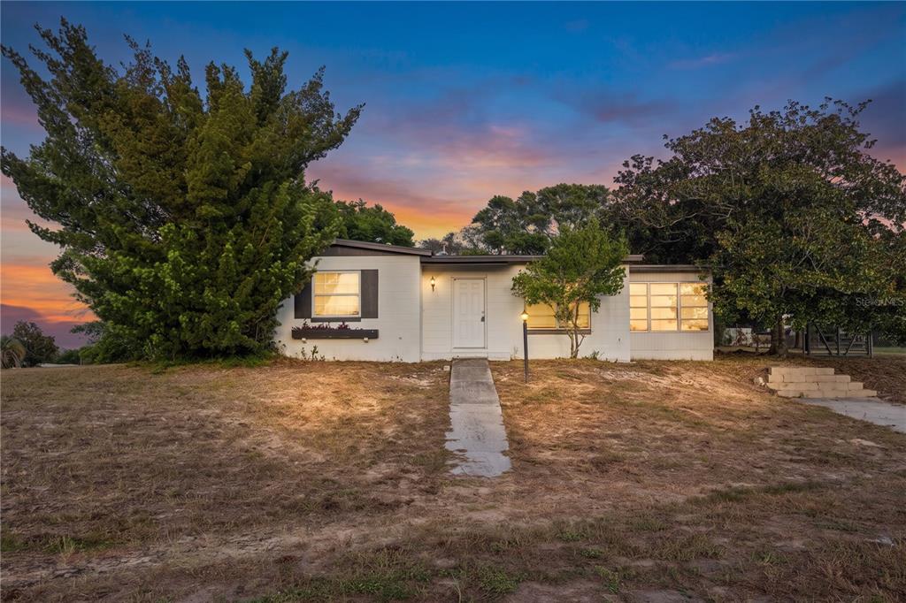 A living room with dark wood floors, beige walls, and an open kitchen with white cabinets — 7045 FIRESIDE STREET, SPRING HILL, FL