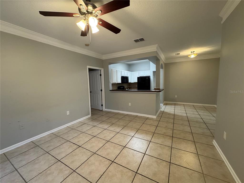 An open-concept living area with tile flooring, a ceiling fan, and a kitchen pass-through window — 12831 MADISON POINTE CIRCLE UNIT 104, ORLANDO, FL
