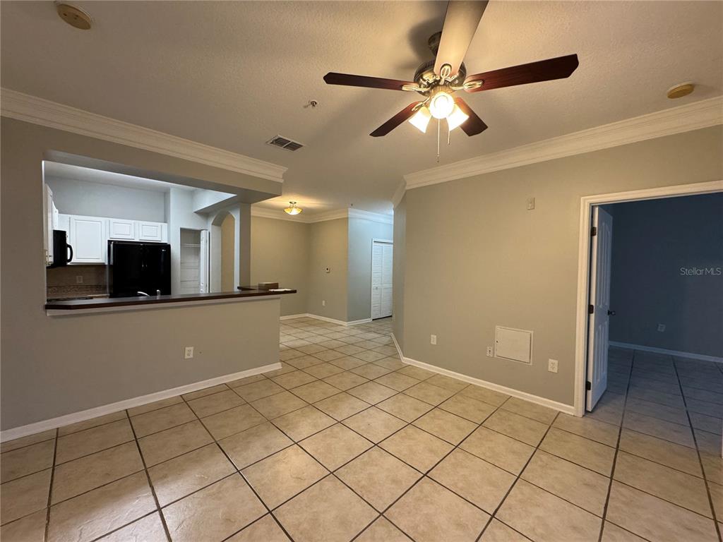 An open-concept living area features tile flooring, a ceiling fan, and a kitchen pass-through — 12831 MADISON POINTE CIRCLE UNIT 104, ORLANDO, FL