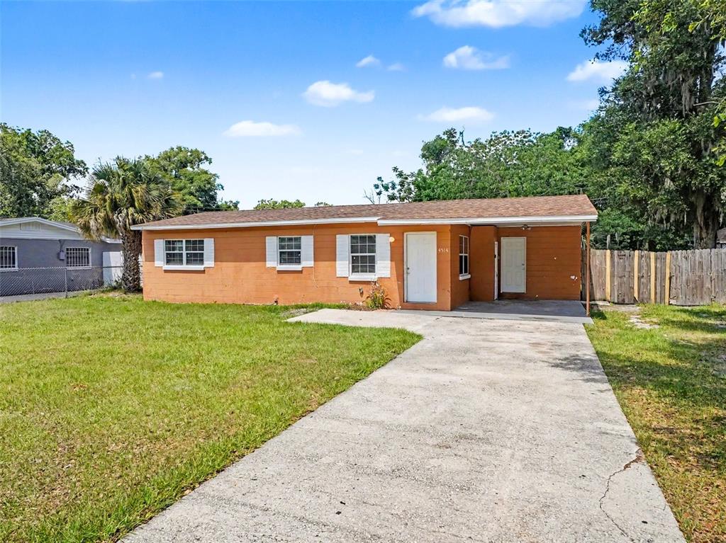 A single-story orange house with a concrete driveway and a covered front porch — 4514 DREXEL AVENUE, ORLANDO, FL