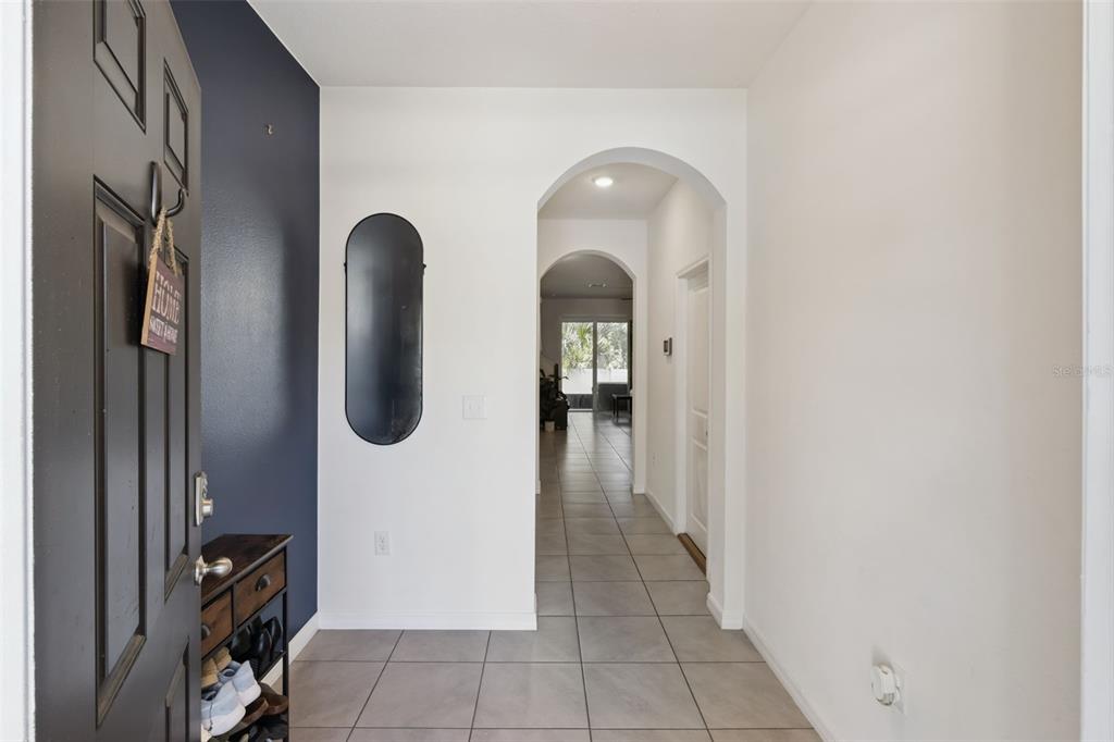 An entryway with tiled floors, a dark accent wall, and an arched hallway leading inside — 3349 PLEASANT WILLOW COURT, BRANDON, FL