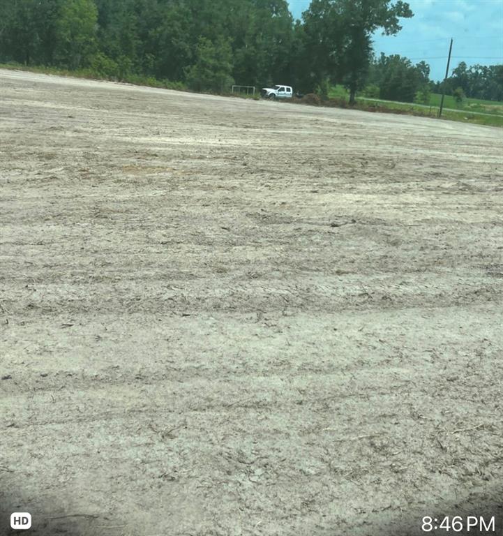 A large, cleared, and leveled dirt lot sits in front of a line of trees — 349C+R6, O'BRIEN, FL