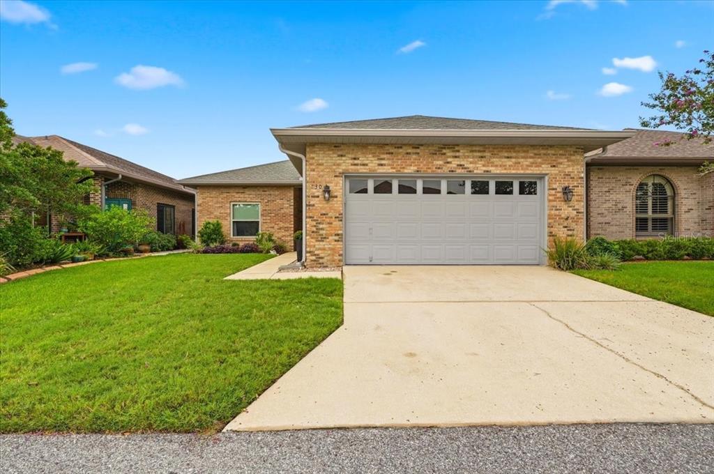 The back exterior of a brick house features a screened-in patio and a grass lawn — 730 MARTINIQUE CIRCLE, LAKELAND, FL