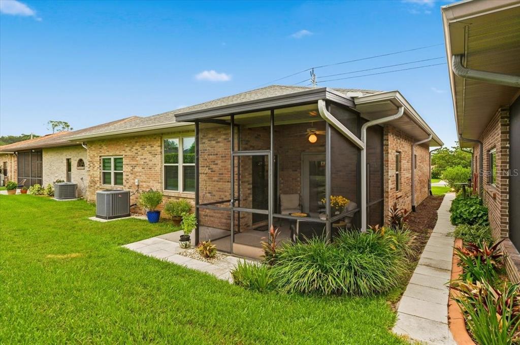 The exterior of a brick house features a screened-in porch and a central air conditioning unit — 730 MARTINIQUE CIRCLE, LAKELAND, FL
