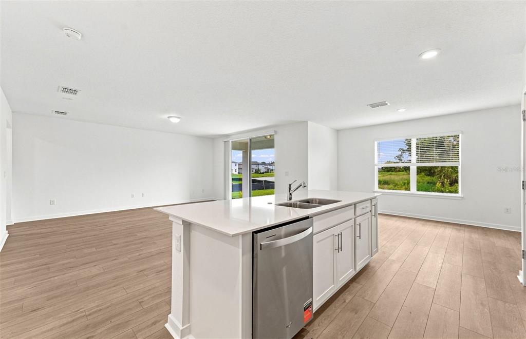 A kitchen with dark wood cabinets, a white island, and an adjacent dining area — 9877 TRELLIS VINE WAY, PARRISH, FL