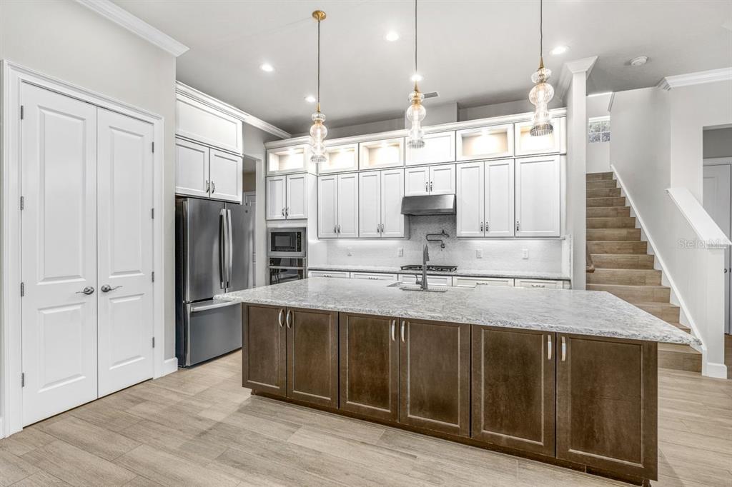 A kitchen features a large island with dark cabinets, white upper cabinets, and stainless appliances — 534 WINGSPAN DRIVE, ORMOND BEACH, FL