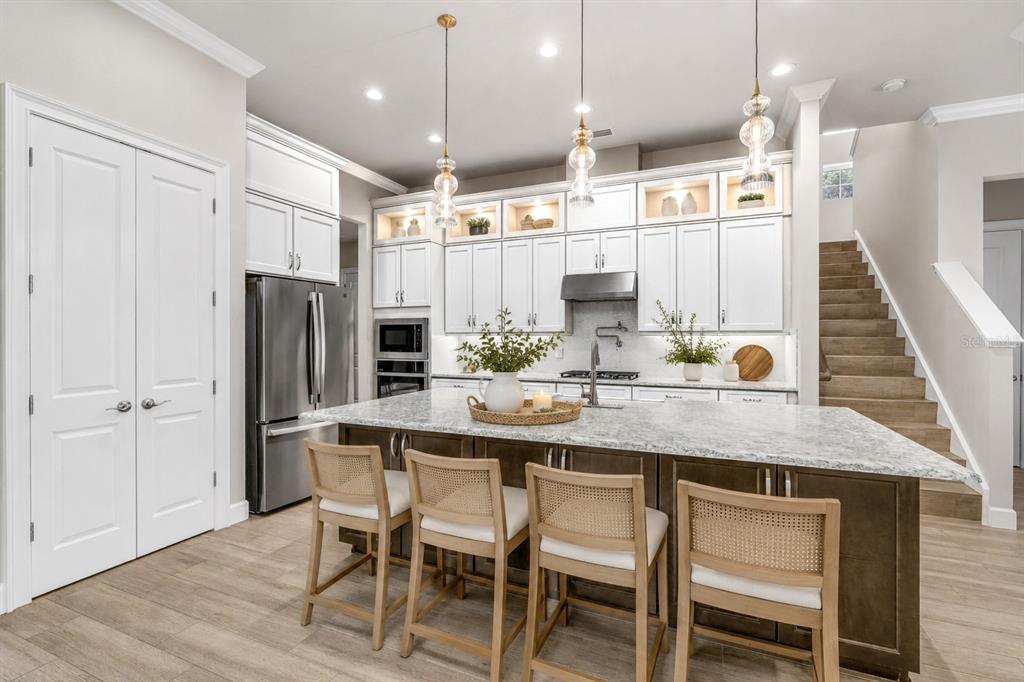 A modern kitchen features white cabinets, a large island with bar seating, and stainless appliances — 534 WINGSPAN DRIVE, ORMOND BEACH, FL
