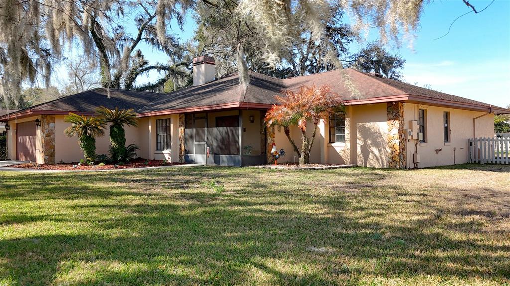 A single-story house with a tan stucco exterior, stone accents, and a screened-in front porch — 452 SUMMIT CHASE DRIVE, VALRICO, FL