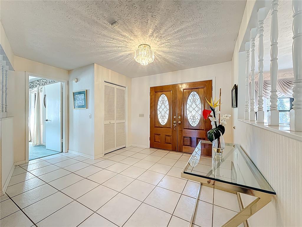 A tiled entryway features a glass console table, double wood doors, and a crystal light fixture — 452 SUMMIT CHASE DRIVE, VALRICO, FL