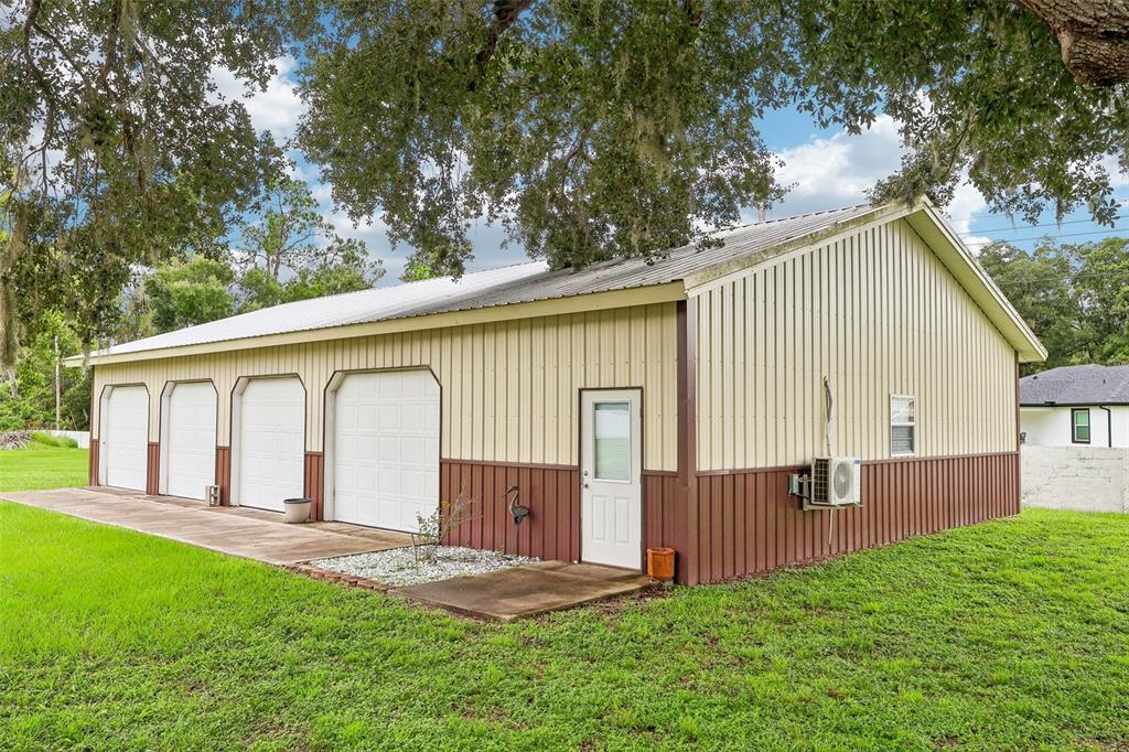 A detached four-car garage with a metal roof sits on a grassy lot — 7026 PINEHAVEN DRIVE, LAKELAND, FL