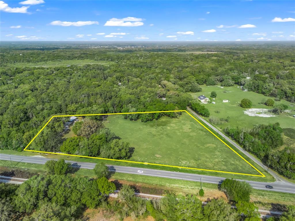 A single-story tan house with a green front door sits on a grassy lot — 8234 S US 301, BUSHNELL, FL
