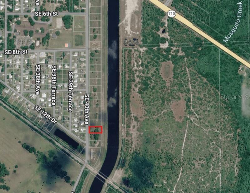 This is an aerial map showing a rectangular property lot highlighted in red near a canal — 1162 SE 40TH AVENUE, OKEECHOBEE, FL