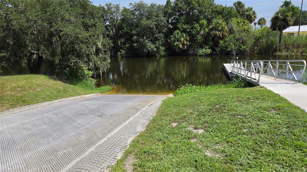 A concrete boat ramp leads into a calm body of water next to a metal dock — 1162 SE 40TH AVENUE, OKEECHOBEE, FL