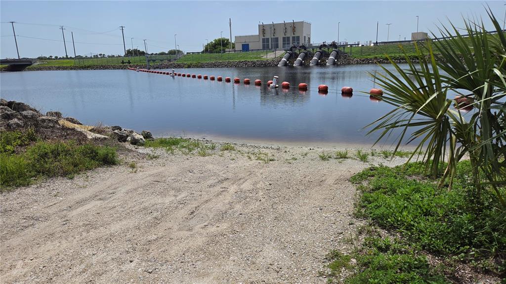 A gravel boat ramp leads into a calm canal with a floating safety barrier — 1162 SE 40TH AVENUE, OKEECHOBEE, FL