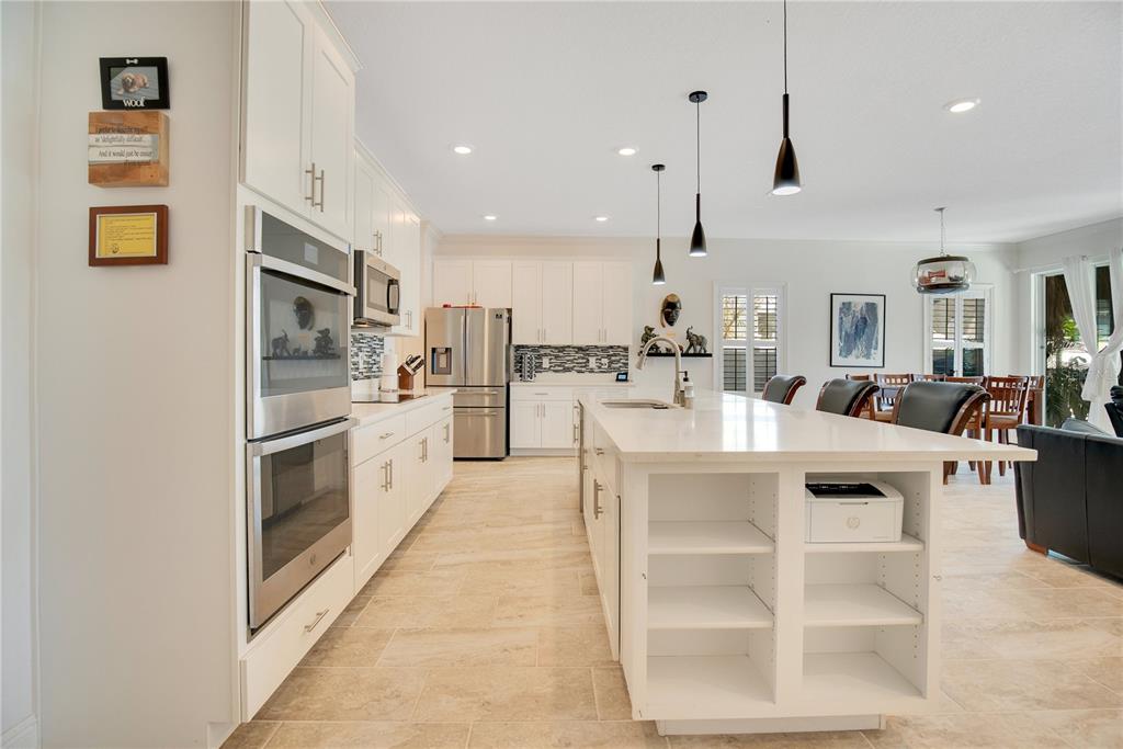 A modern kitchen features white cabinetry, stainless steel appliances, a large island, and tile flooring — 260 JACKSON LOOP, DELAND, FL