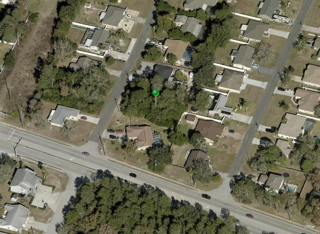 This aerial view shows a wooded residential lot marked with a green pin — 4436 AZORA ROAD, SPRING HILL, FL