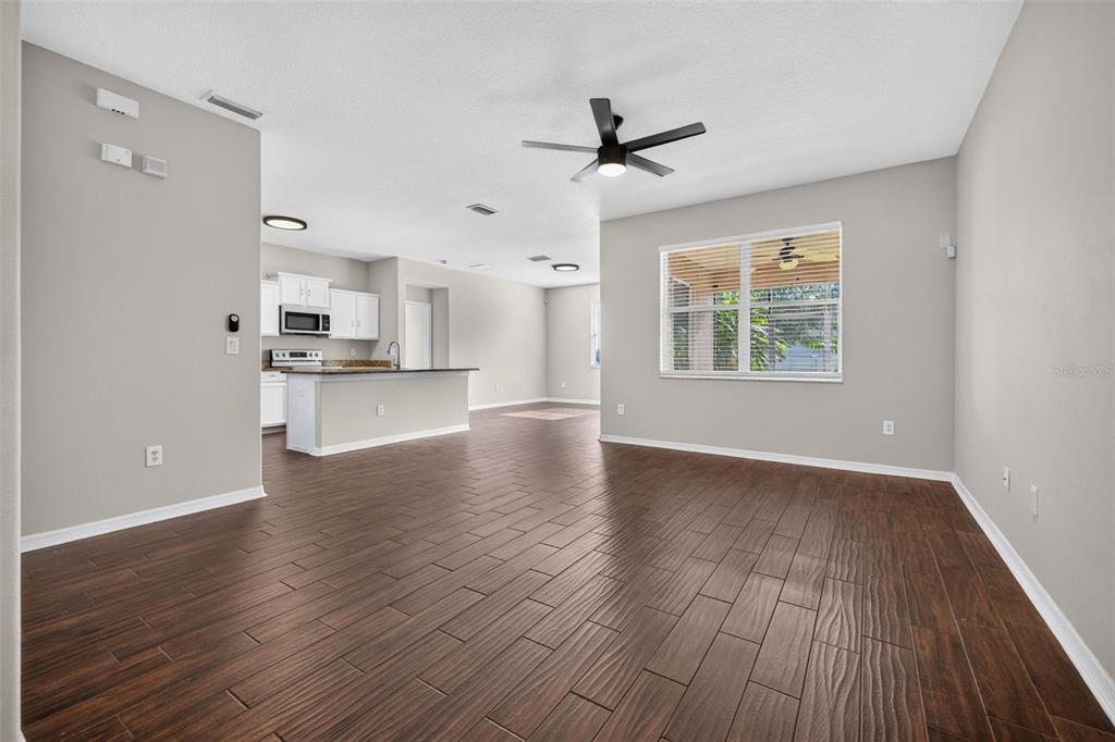 An open-concept living area with dark wood-look tile flooring, a ceiling fan, and a kitchen — 14013 HOLLOW LEAF PLACE, RIVERVIEW, FL