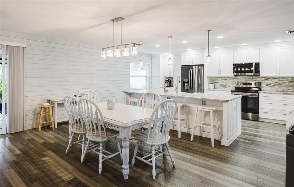 A covered patio features a stone-bordered pond with a fountain and a wooden porch swing — 625 E BAFFIN DRIVE, VENICE, FL