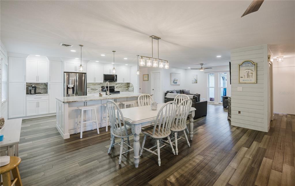 A living room with dark leather sofas, a glass coffee table, and an open kitchen — 625 E BAFFIN DRIVE, VENICE, FL
