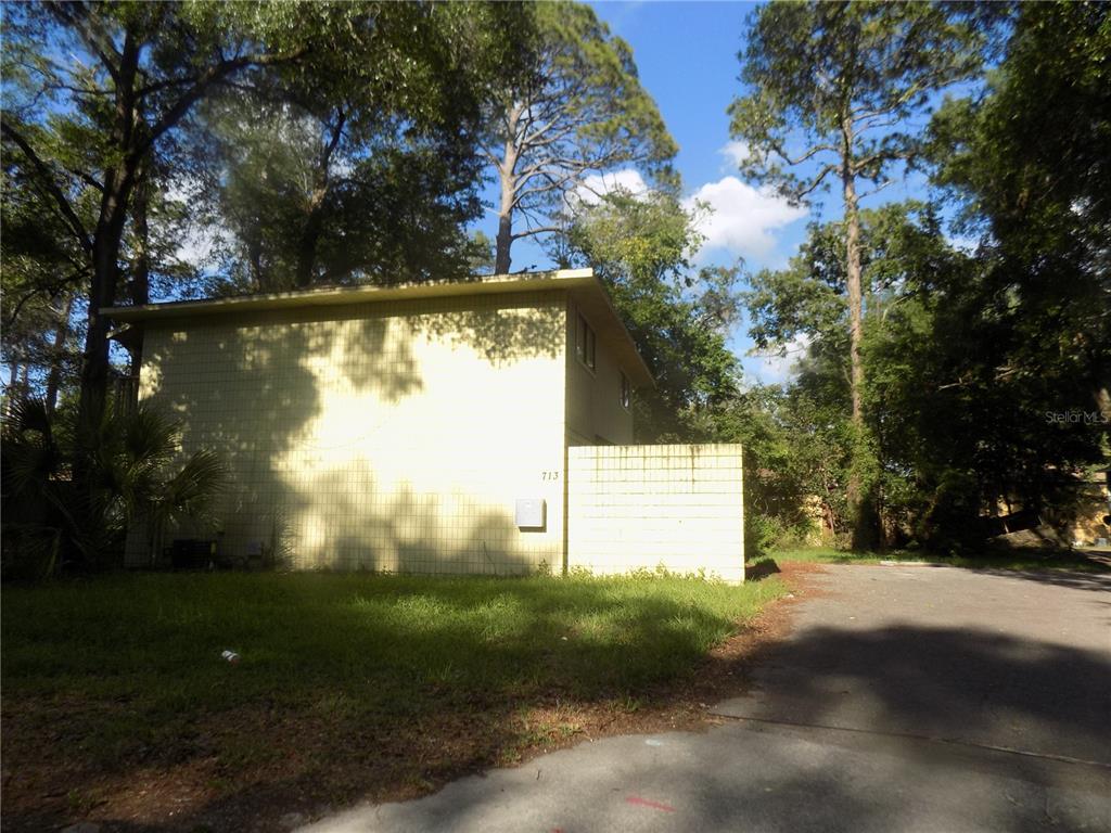A two-story building with yellow block siding stands next to a paved driveway — 713 SW 69 STREET, GAINESVILLE, FL