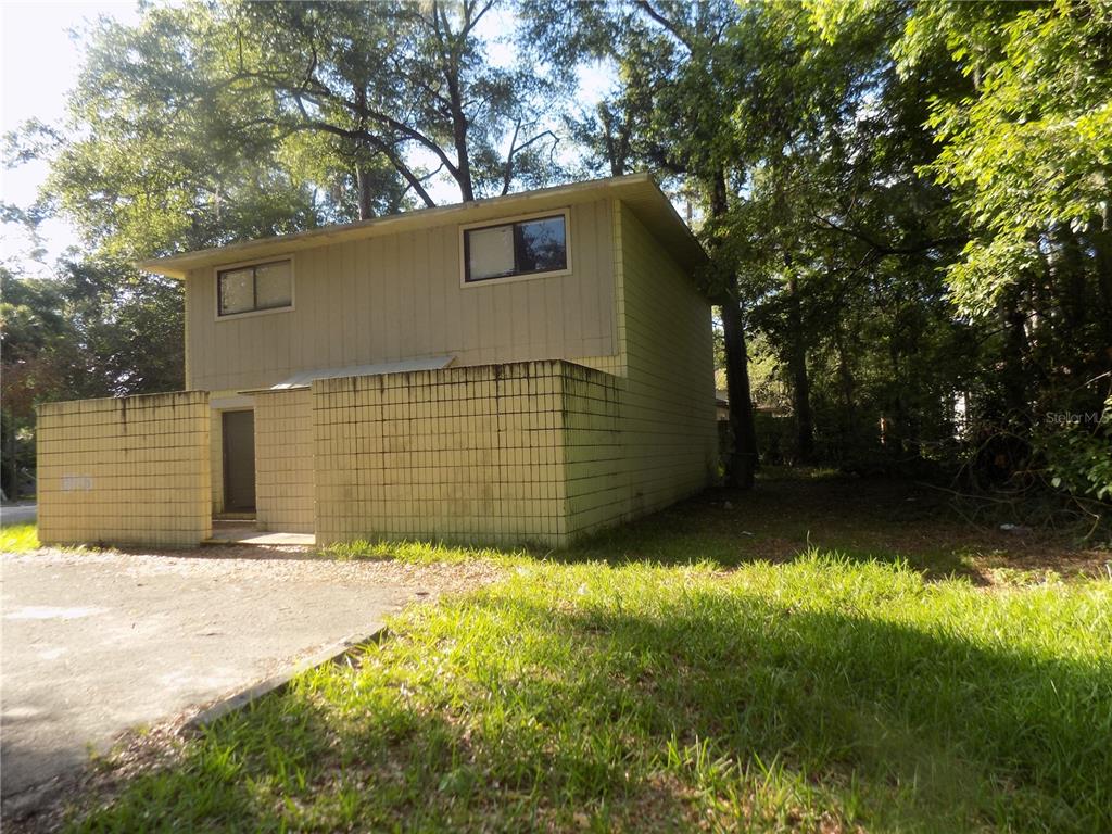 A two-story house with a yellow tiled privacy wall and a paved driveway — 713 SW 69 STREET, GAINESVILLE, FL