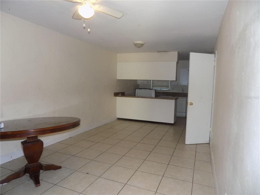 A dining area with tile floors and a ceiling fan opens to a kitchen counter — 713 SW 69 STREET, GAINESVILLE, FL